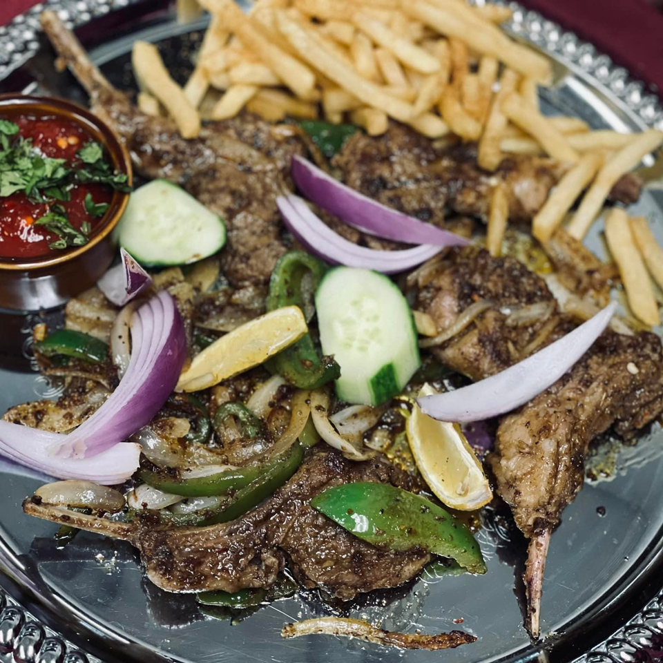 Indian lamb chops with fries, red onion, bell peppers, and a side of red sauce.